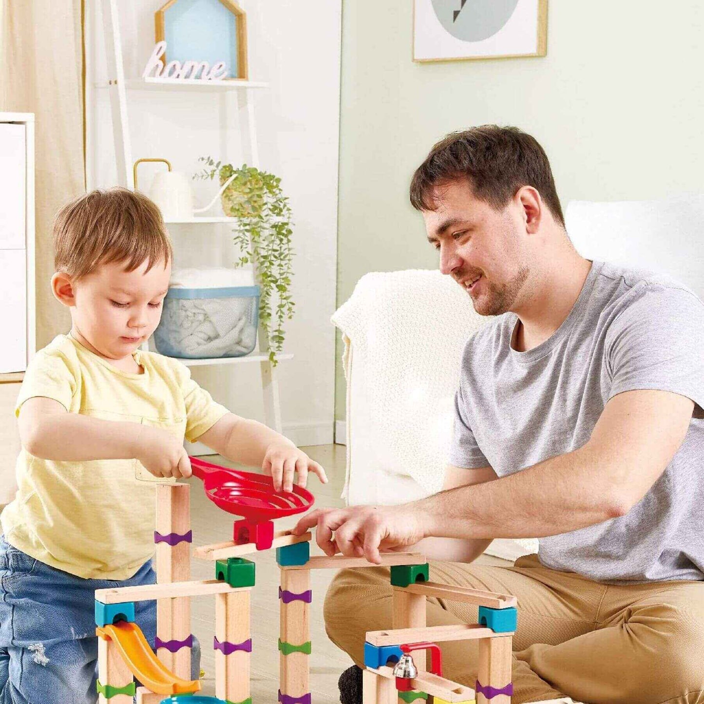 Man and child playing with Hape Tricks n Twists Marble Track in a home setting.