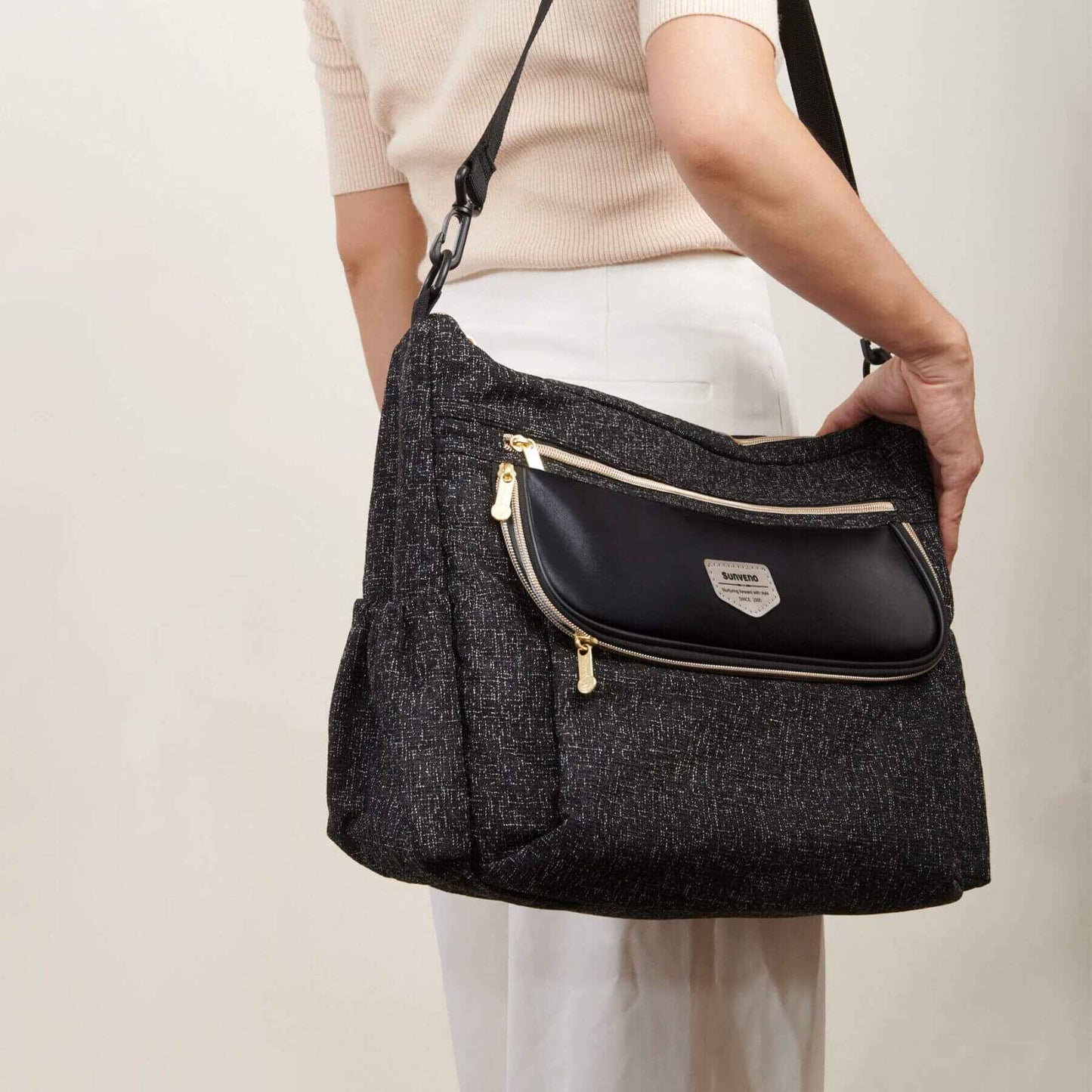 Person holding Tweed Luxe Stroller Organizer Black with a beige background