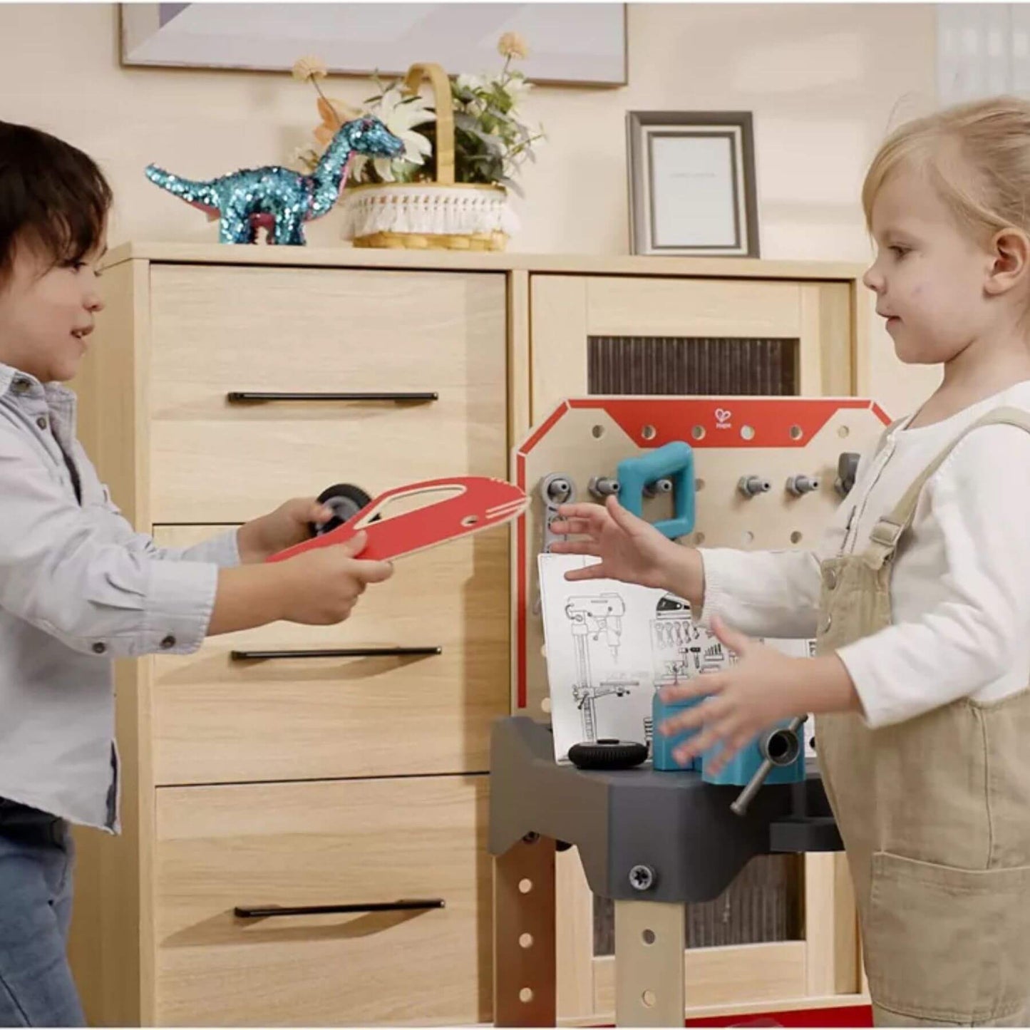Two children playing with Hape Vehicle Service & Repair Workbench in a room with wooden furniture.
