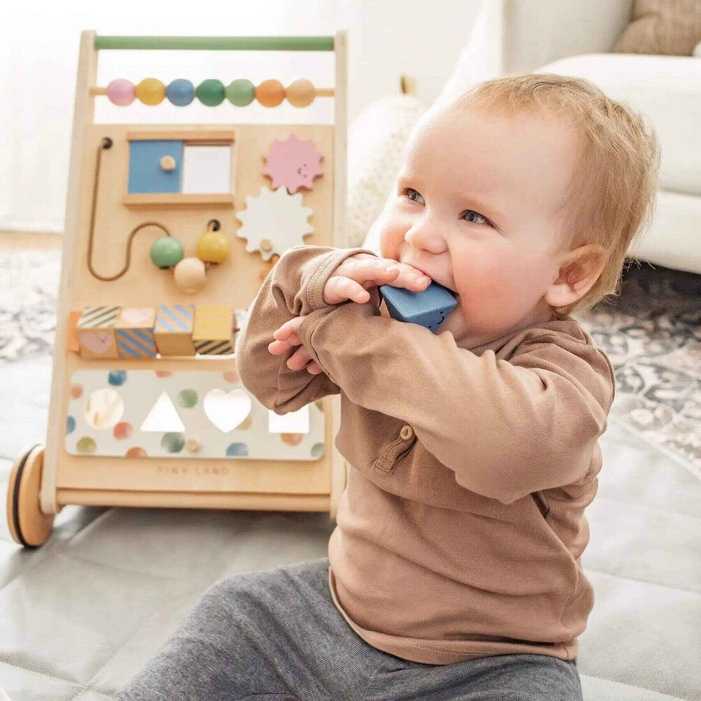 Baby playing with Tiny Land® Versatile Natural Wooden Baby Walker on a bed