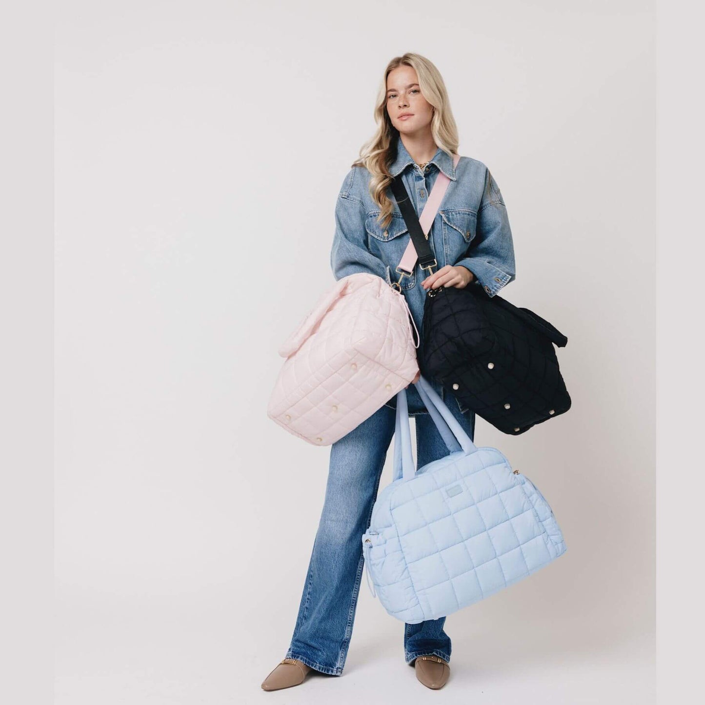 Woman holding three augustnoa the weekender duffle bags in different colors