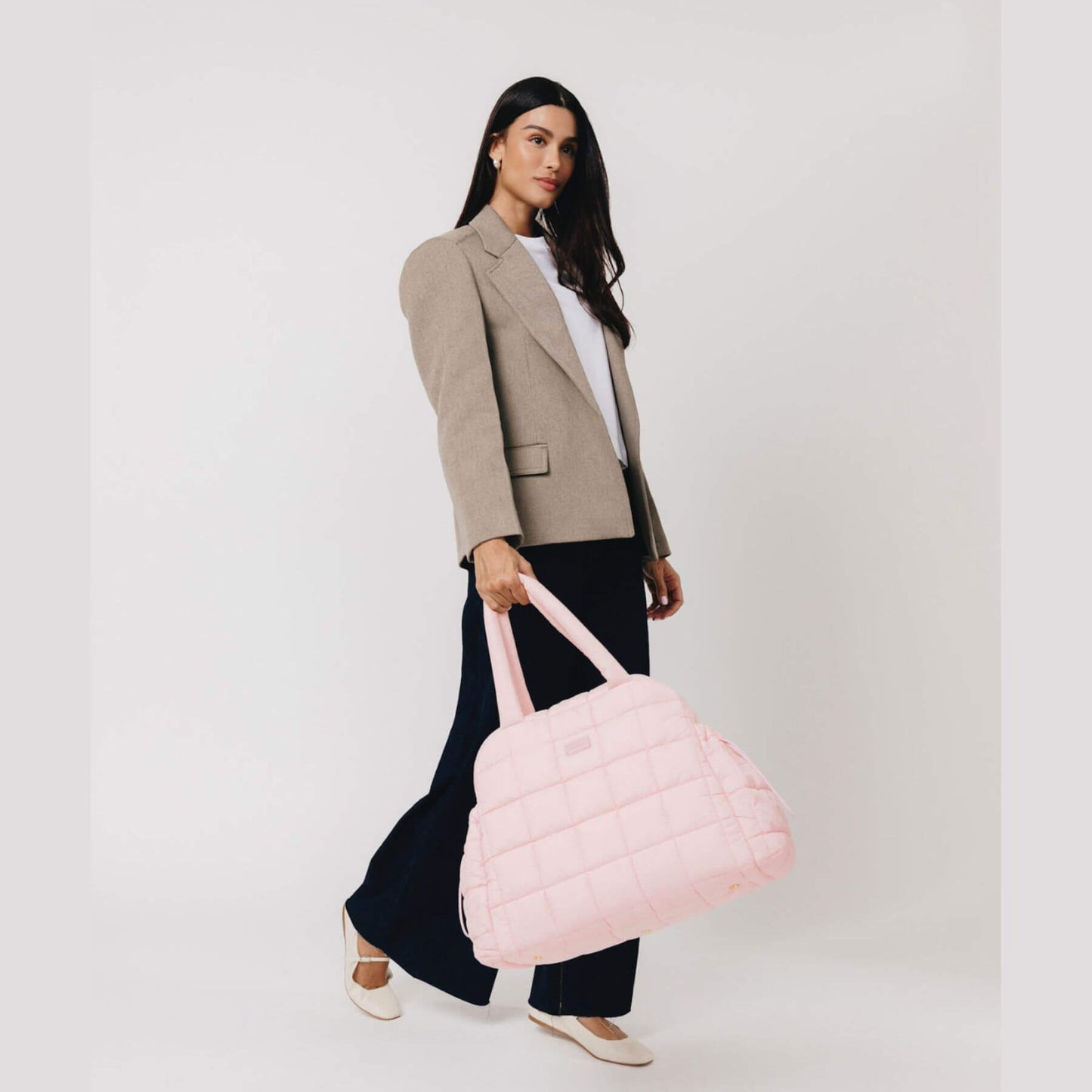 Woman holding augustnoa the weekender duffle bag pink against a white background
