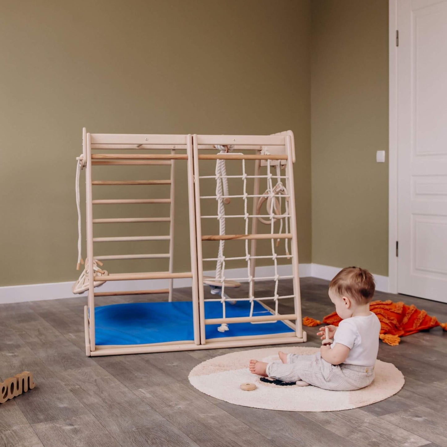 Baby Sitting in front of Wood and Hearts Indoor Jungle Gym - Trapeze + 4 Rope