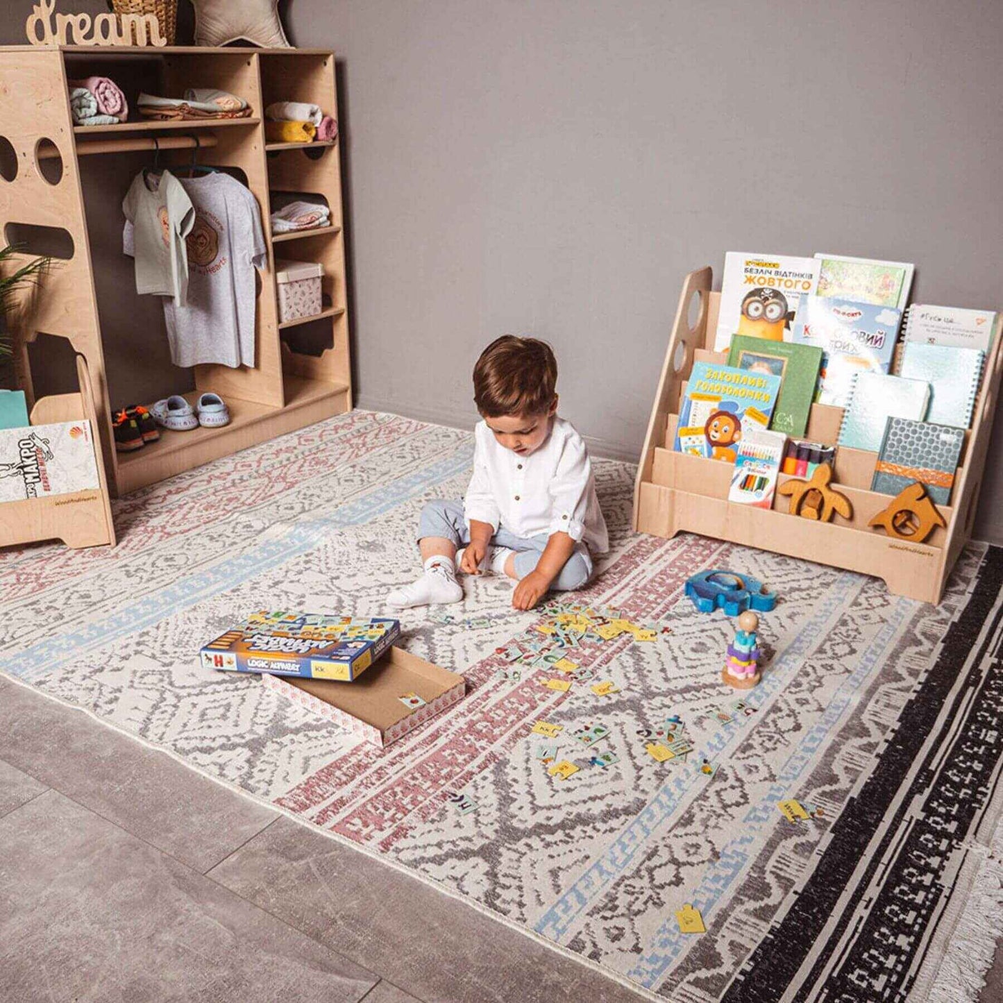 Boy Playing Next to Wood and Hearts Montessori Bookshelf Natural