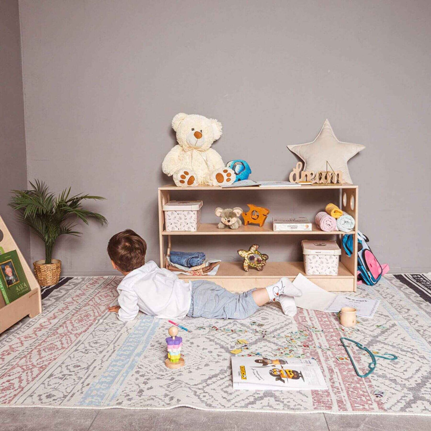 Boy Lying next to Wood and Hearts Montessori Shelf