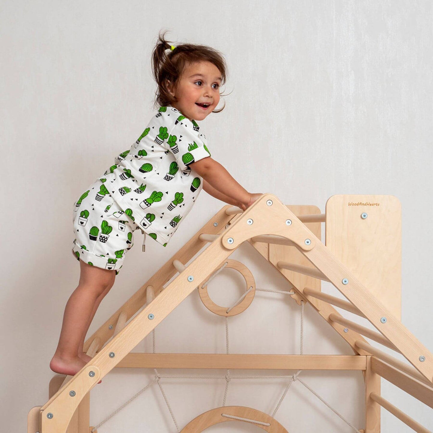 Girl Climbing on Top of Wood and Hearts Wooden Climbing Playhouse Natural