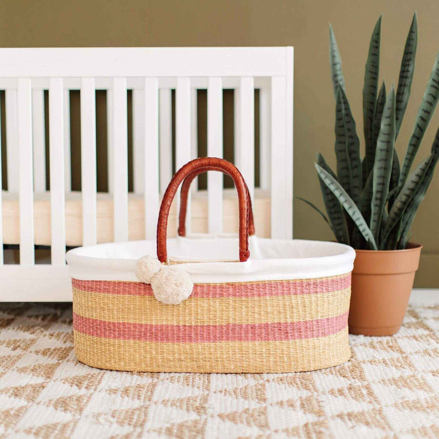 Wildflower No Hood African Moses Basket on a checkered floor in front of a white crib.