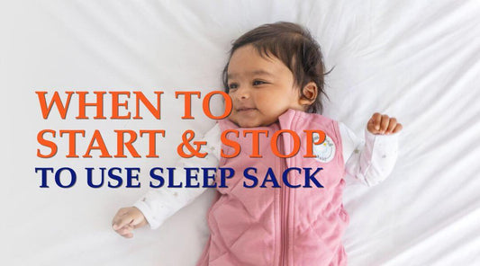 baby in a pink sleep sack on bed