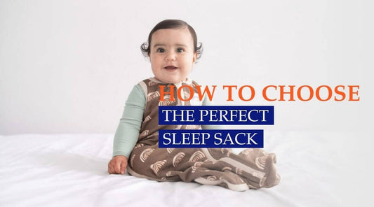 baby in sleep sack sitting on bed