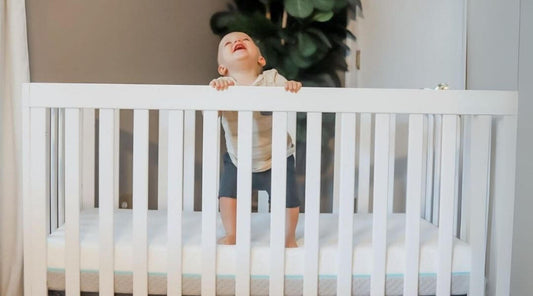 baby standing on mattress, inside crib