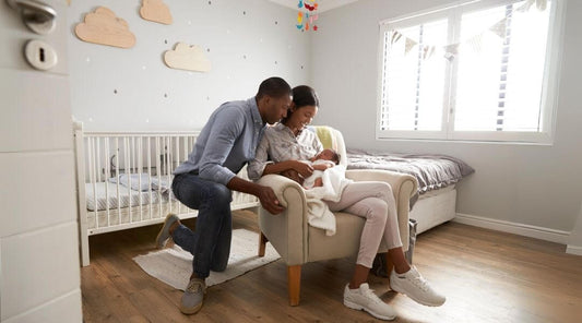 Dad & Mom holding baby on a nursery chair