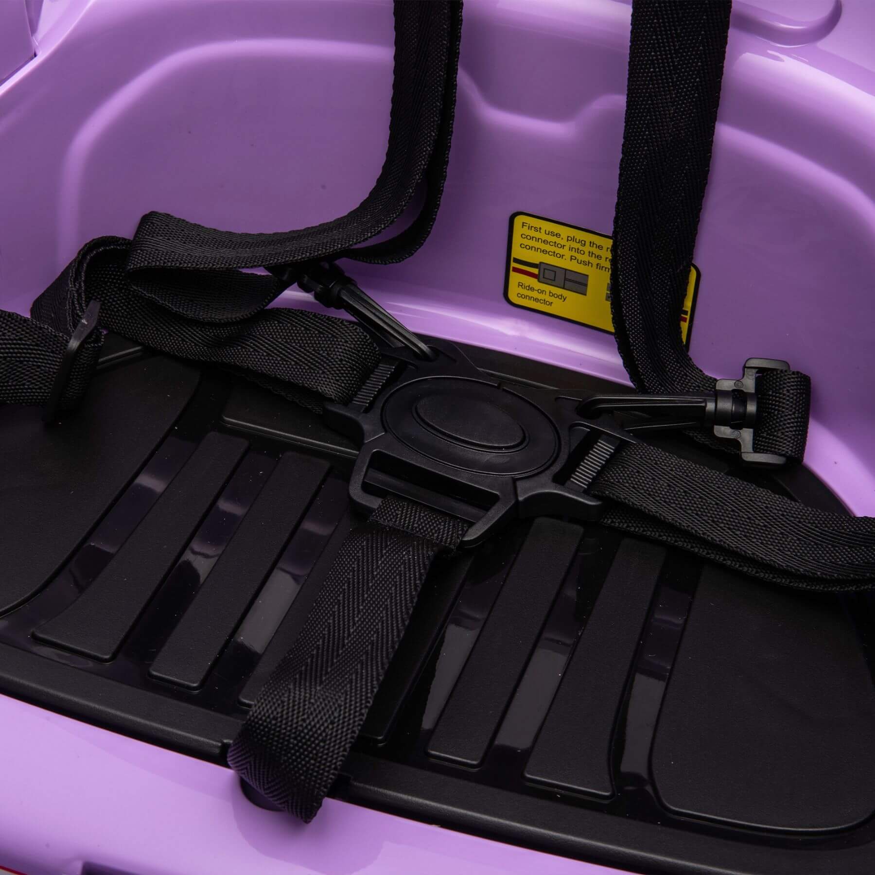 Black seat belt retractor on a purple car seat with a visible warning label.