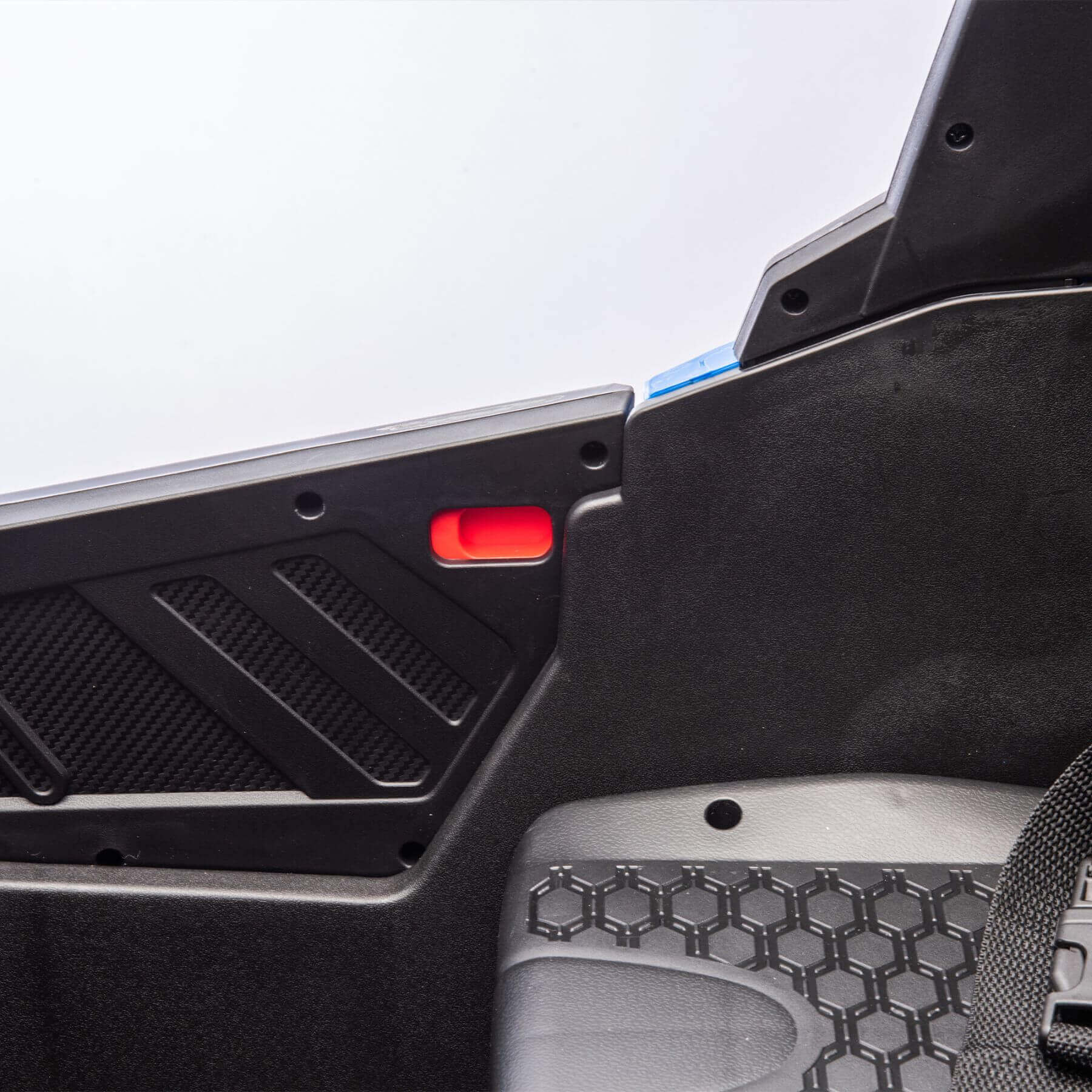 Close-up of a car's interior panel with a red light and honeycomb pattern.