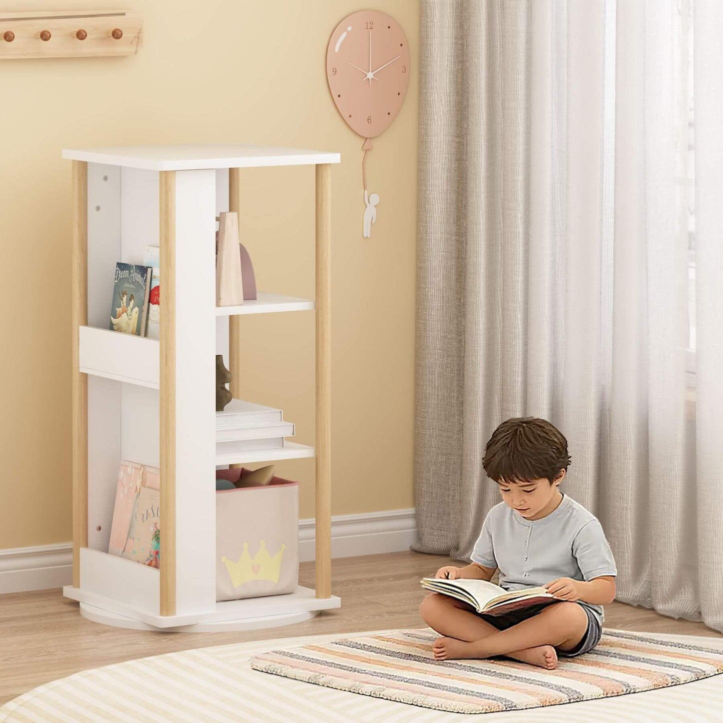 Child reading a book on a striped rug in a room with MOONRIVER 360° Rotating Kids Bookshelf and pink balloon.