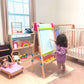 Child drawing on Tiny Land® 3-in-1 Art Easel & Paper Roll Set in a nursery with toys and furniture around