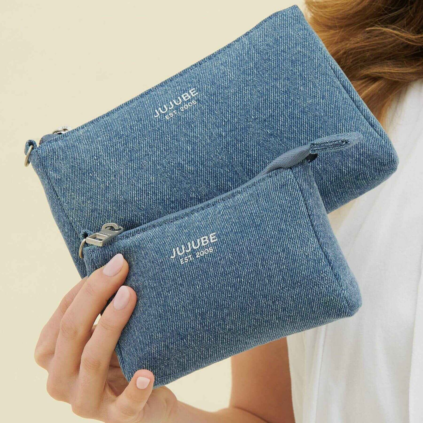 Blue pouches with 'JUJUBE' branding held by a person against a neutral background