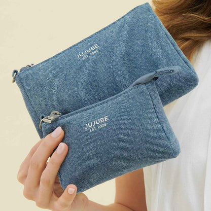 Blue pouches with 'JUJUBE' branding held by a person against a neutral background