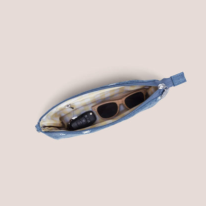 Blue pouch with sunglasses and phone inside on a beige background