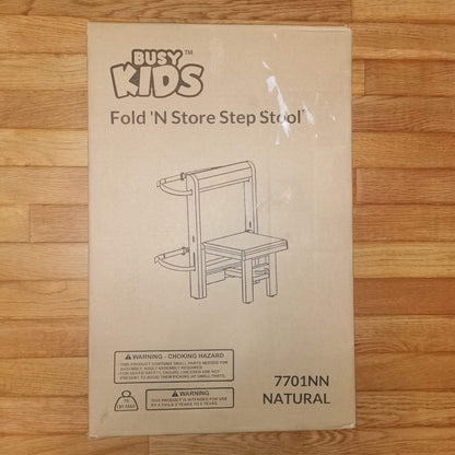 A cardboard product box for a Busy Kids Fold 'N Store Step Stool, shown on a light wood floor.