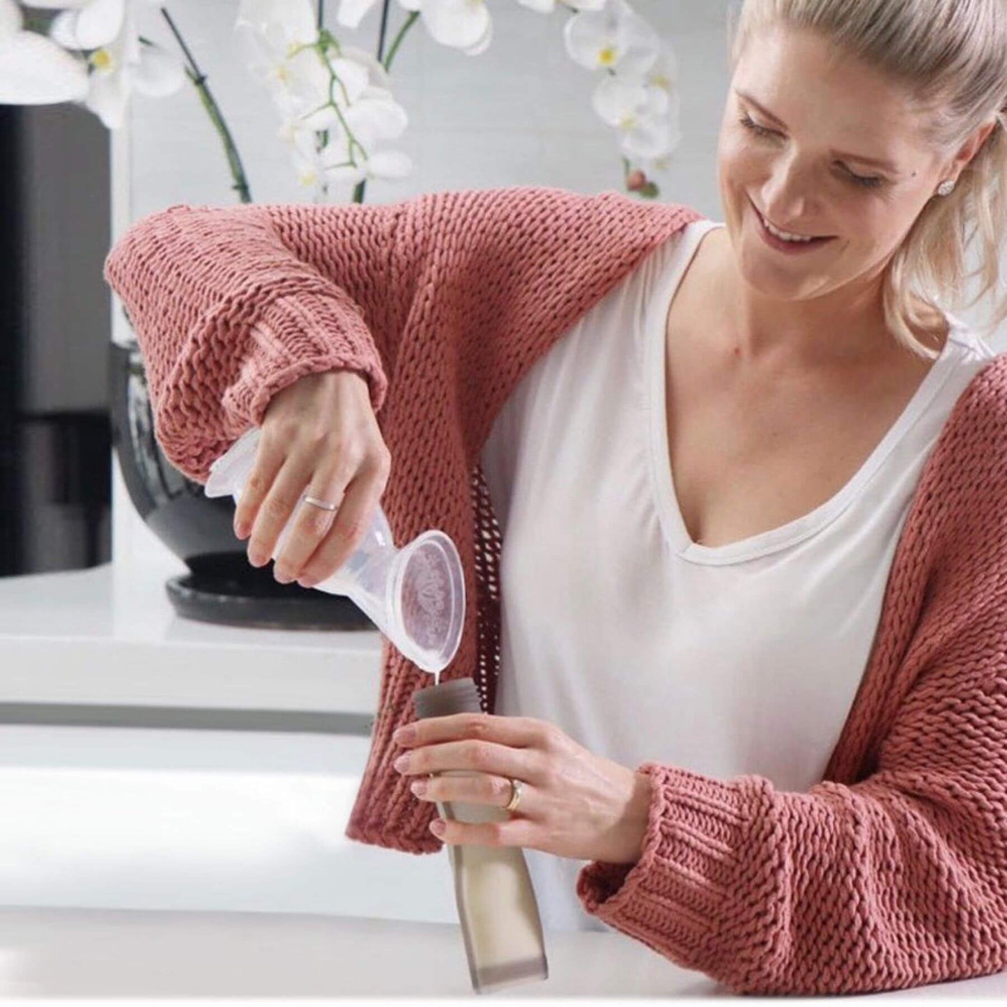 Woman pouring milk into Haakaa Silicone Milk Storage Bag 9oz