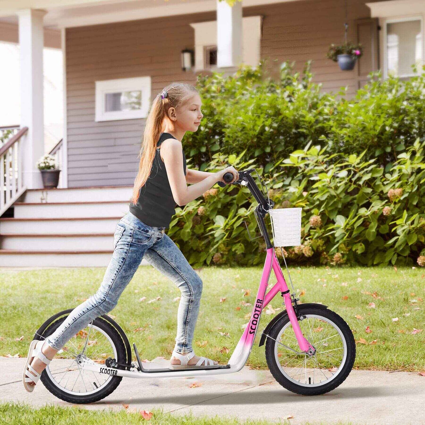 Girl riding Aosom Youth Scooter - Pink on a sidewalk with a house and greenery in the background