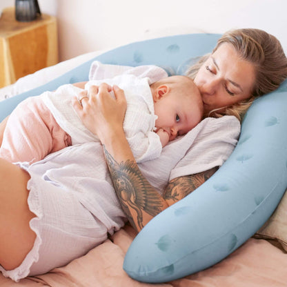Woman holding a baby wrapped in a white blanket on B.Love U-Shape Pregnancy Pillow - Blue