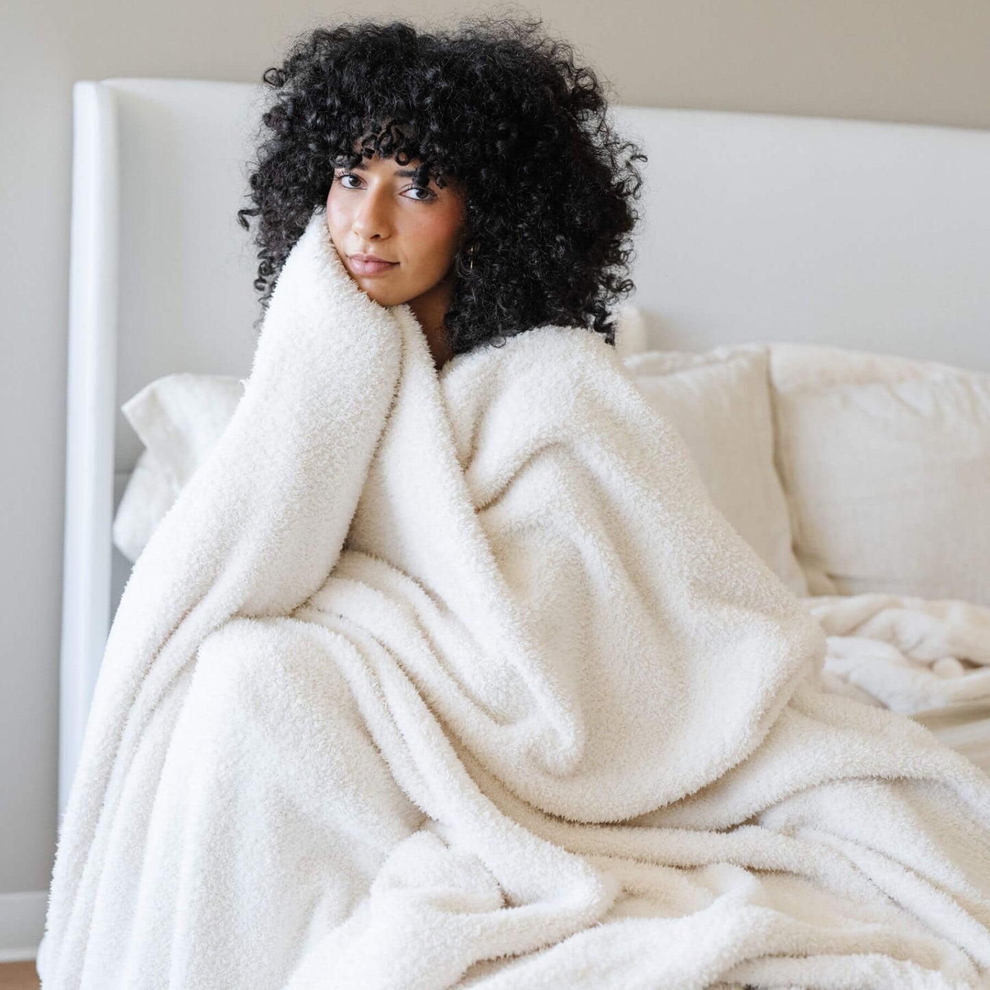 Woman wrapped in BAMBONI® XL Blanket - Ivory on a couch