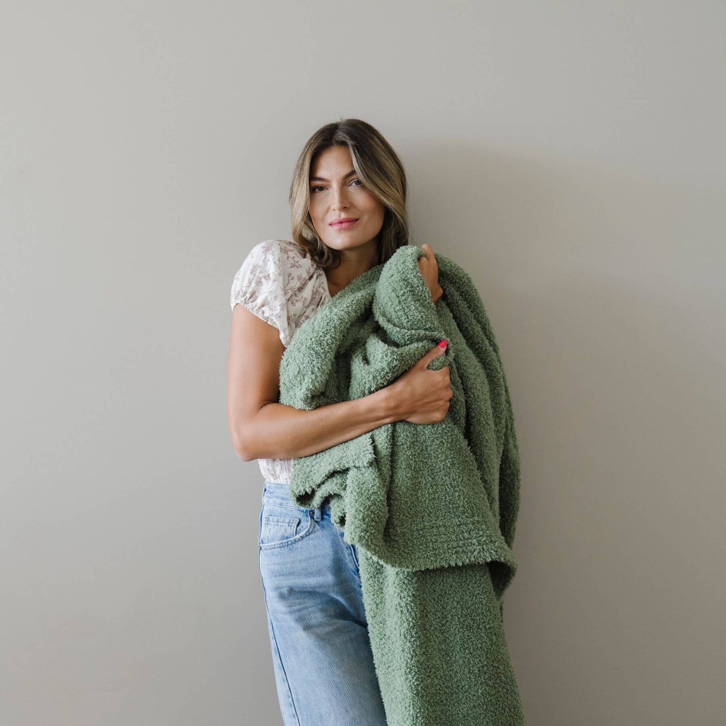 Woman holding BAMBONI® XL Blanket - Olive against a plain background