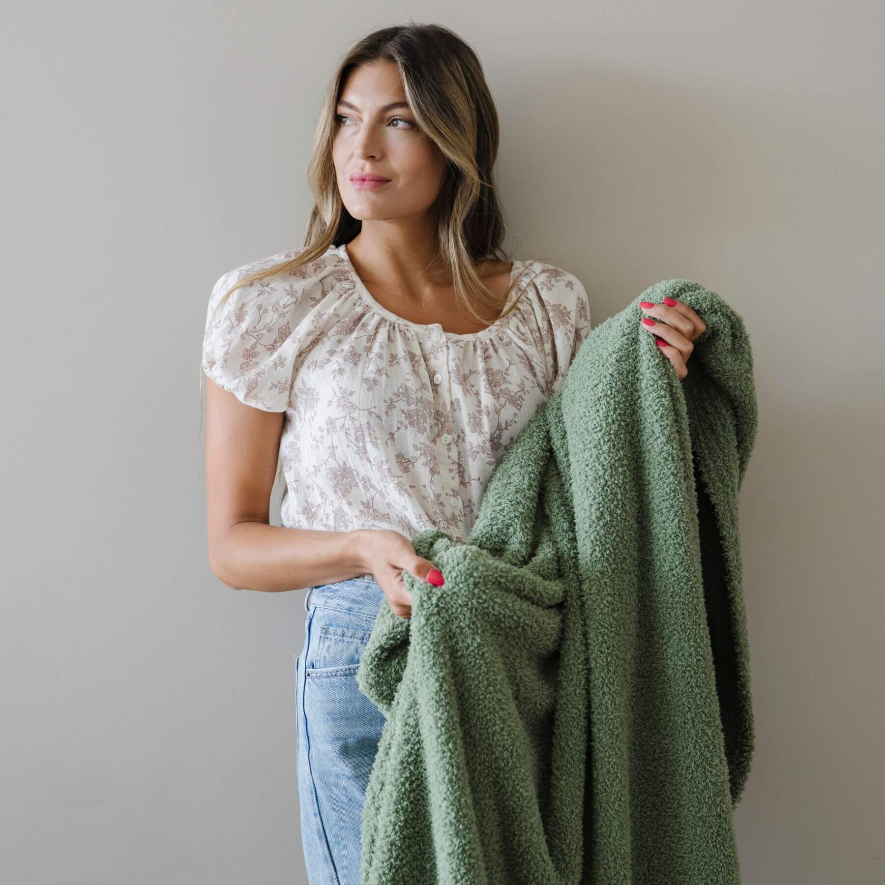 Woman holding BAMBONI® XL Blanket - Olive against a plain background