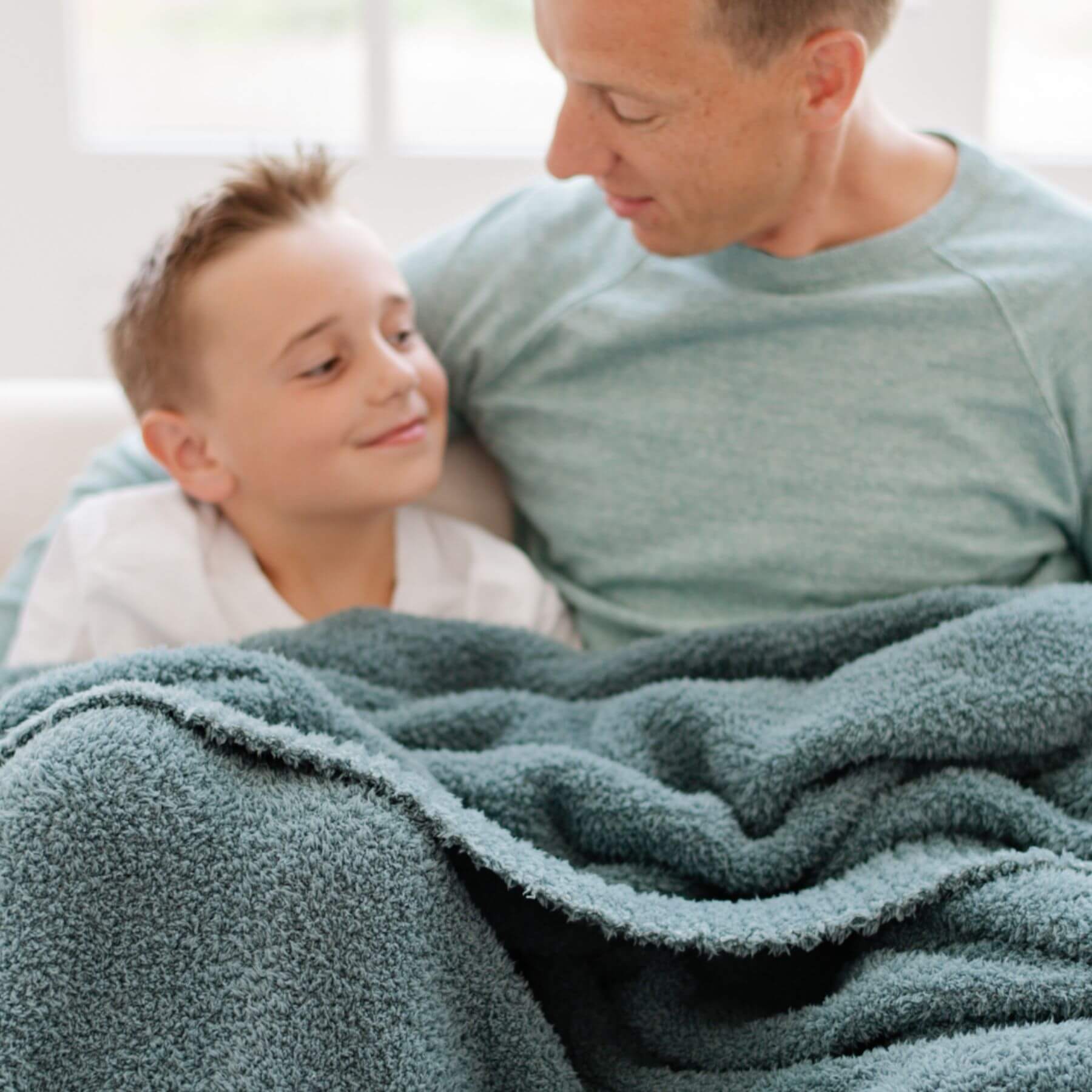 Man and child under BAMBONI® XL Blanket - Spruce, smiling and looking at each other