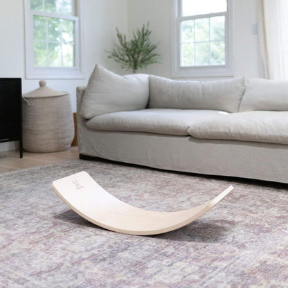Light gray sofa in a living room with a curved wooden board on a patterned rug.