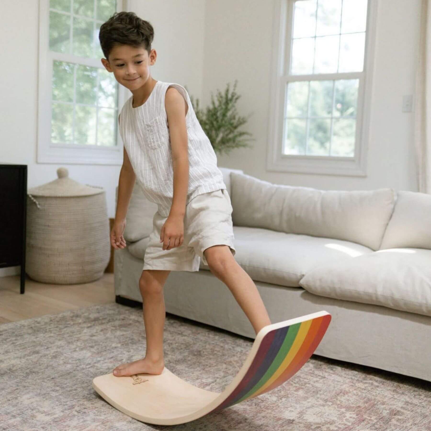 Child standing on a rainbow-colored balance board in a living room.