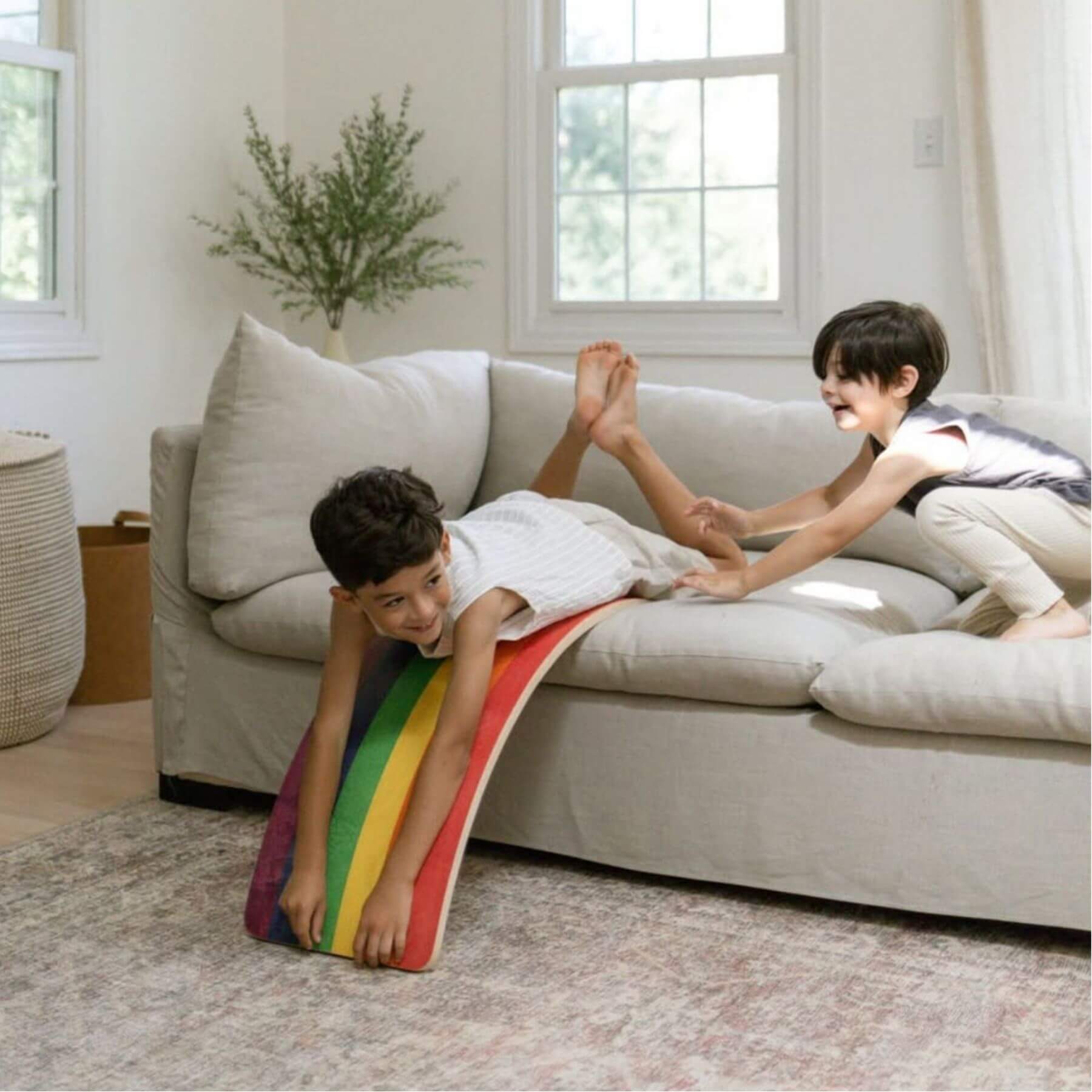 Two children playing with a colorful slide on a couch in a living room.