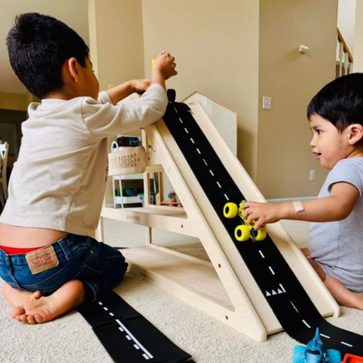 Two children playing with toy cars on CAMDEN- Toy Car Storage + Ramp indoors.