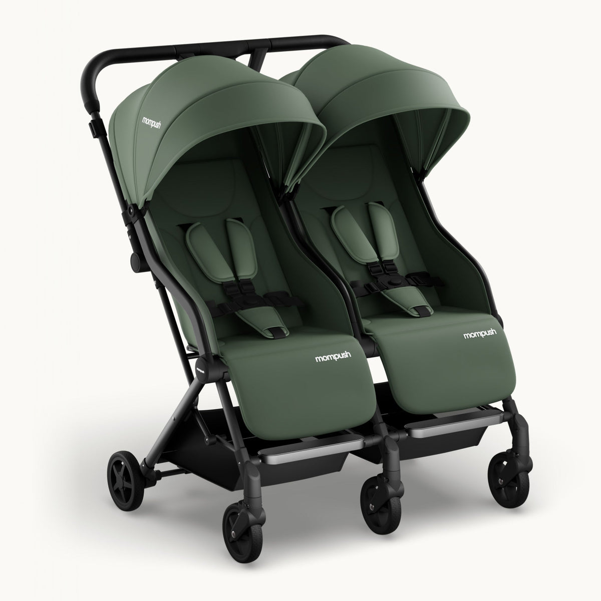 A double stroller in sage green fabric with a black frame and wheels, shown from a three-quarters angle on a light off-white background. The brand name 'monpush' is visible on the side of the stroller seats.
