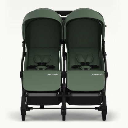 A twin infant stroller in sage green fabric with a black frame, shown from the front against a light gray background. The brand name 'mompush' is visible on the front of each seat.
