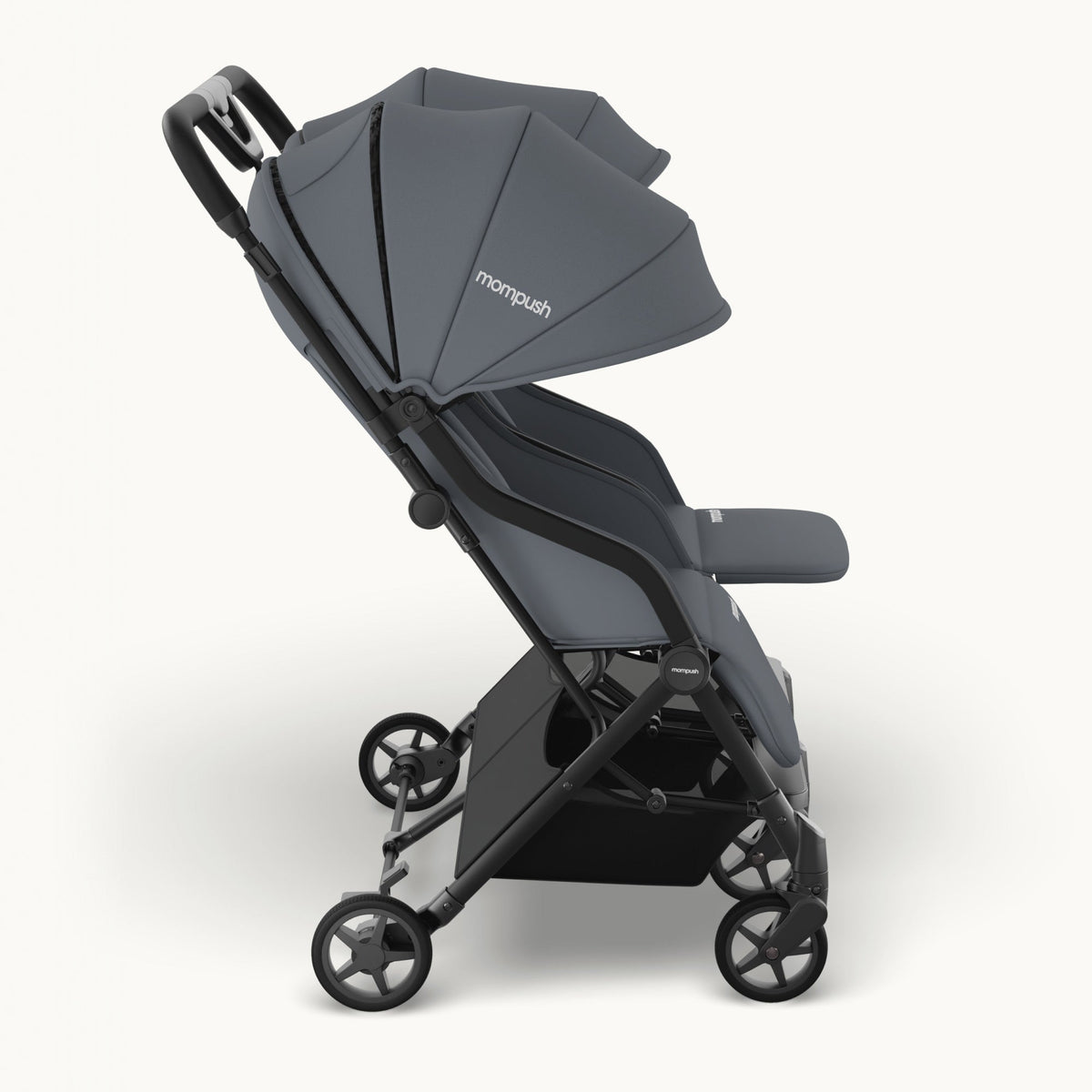 A compact double stroller in dark gray fabric and black frame, shown from a three-quarter side view against a clean off-white background. The brand name 'monpush' is visible on the canopy.