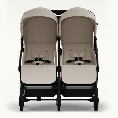 A front-facing view of a double stroller with two beige seats and canopies, a black frame, and black wheels, set against a plain light background.