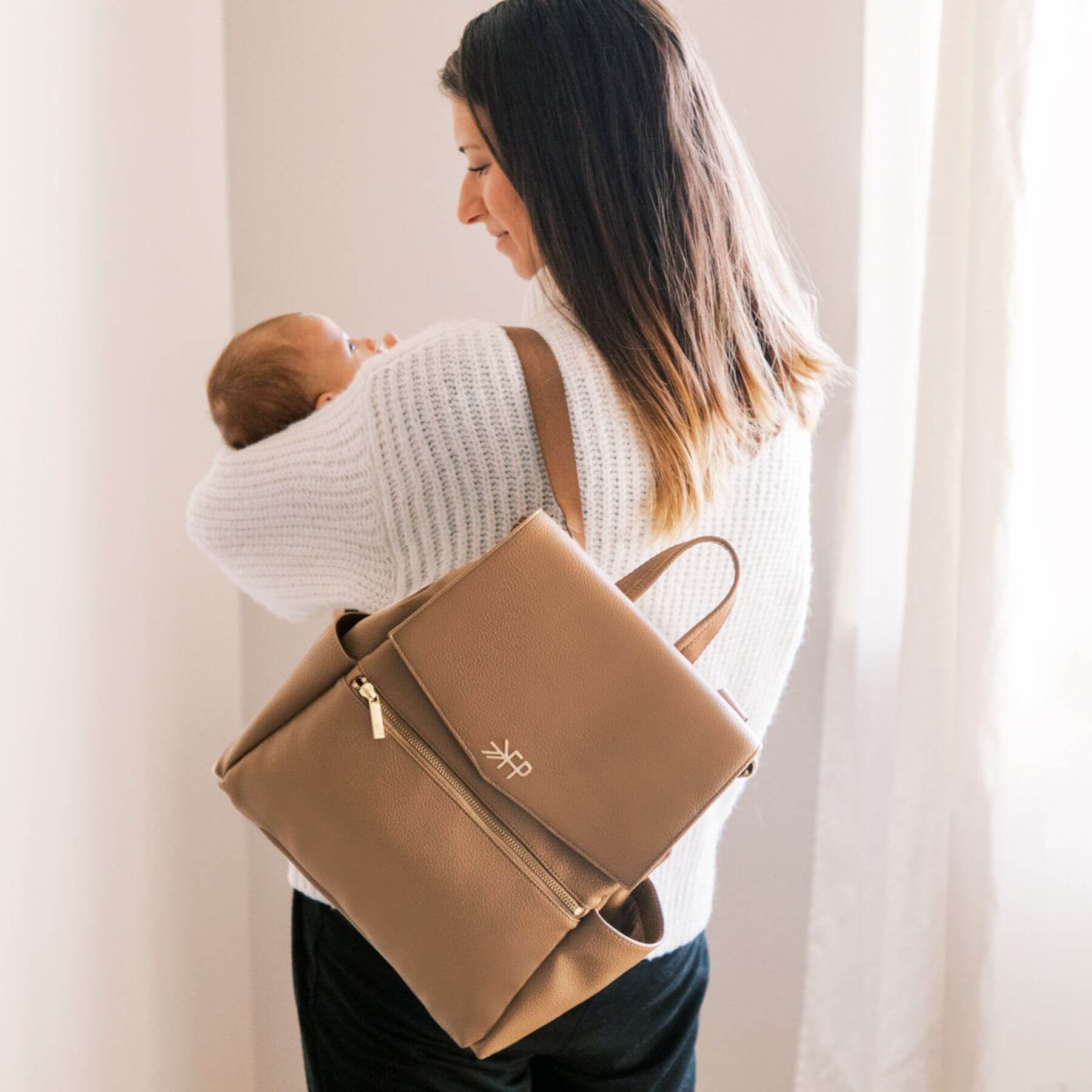 Woman carrying a baby and Freshly Picked Toffee Mini Classic Diaper Bag II
