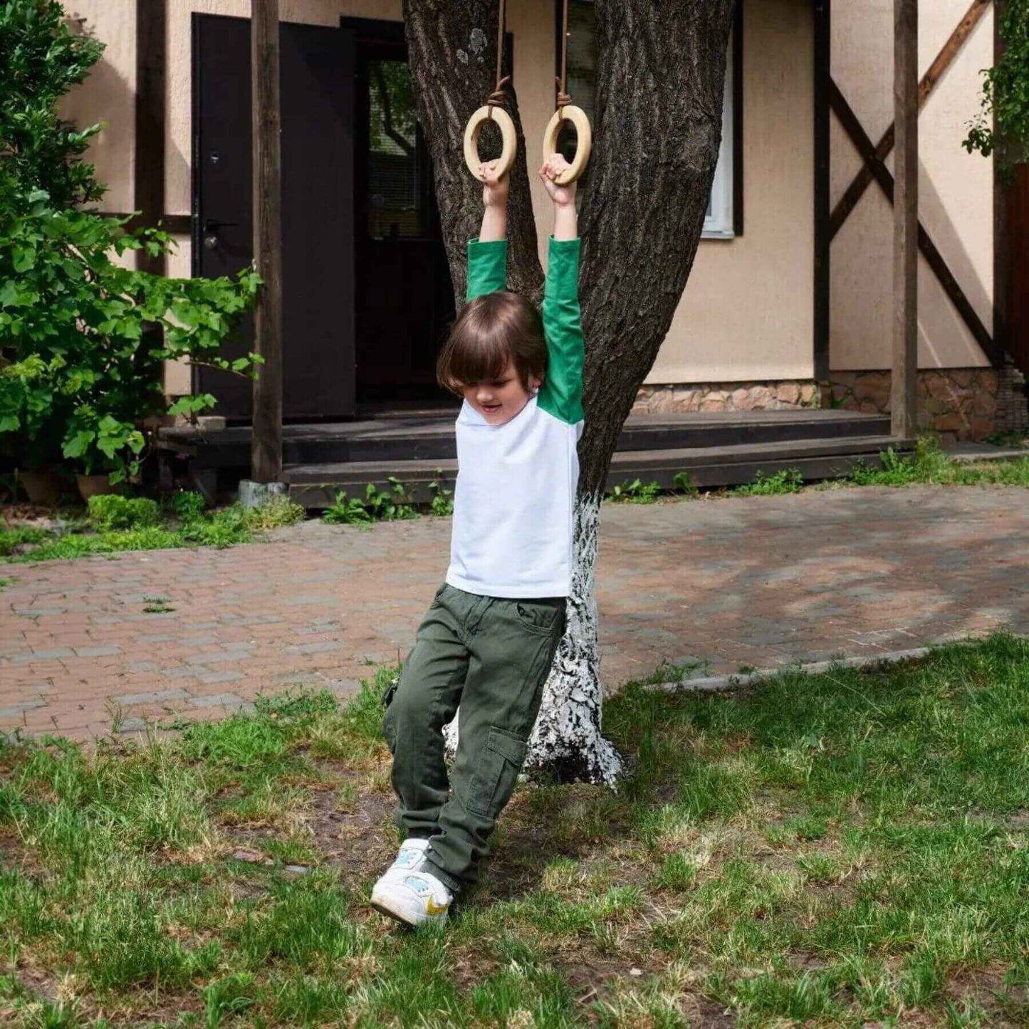 Kid playing with Goodevas Wooden Gymnastic Ring on a tree outside