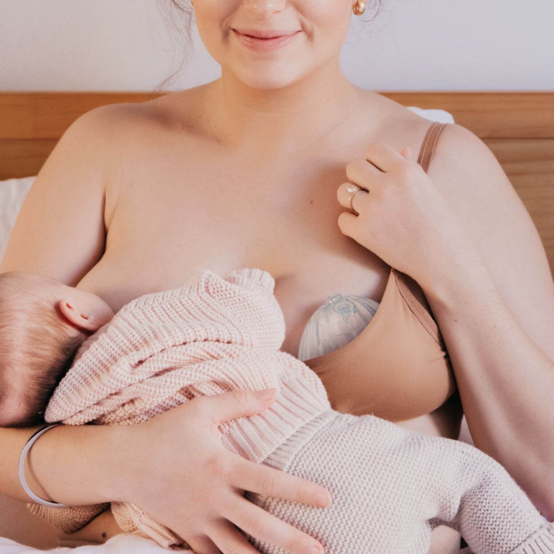 Woman breastfeeding a baby wrapped in a pink blanket.