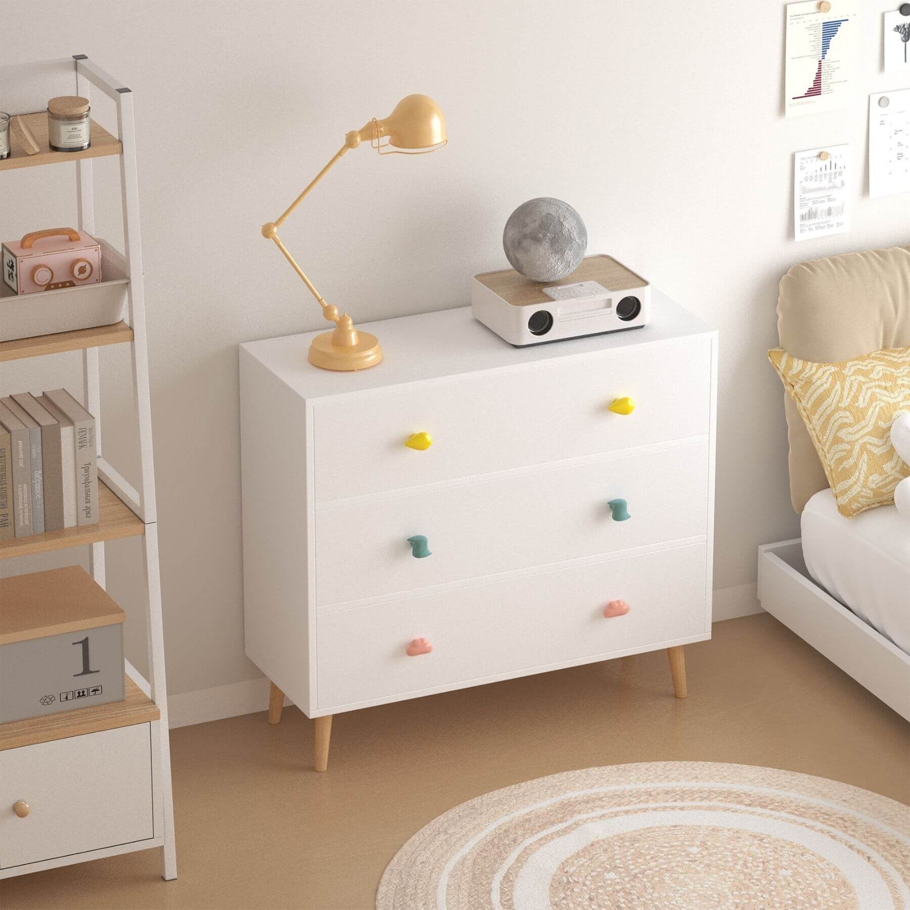 White dresser with colorful knobs in a room with a lamp and books.