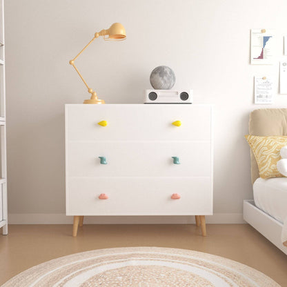 White dresser with colorful knobs in a room with a lamp and decor items.