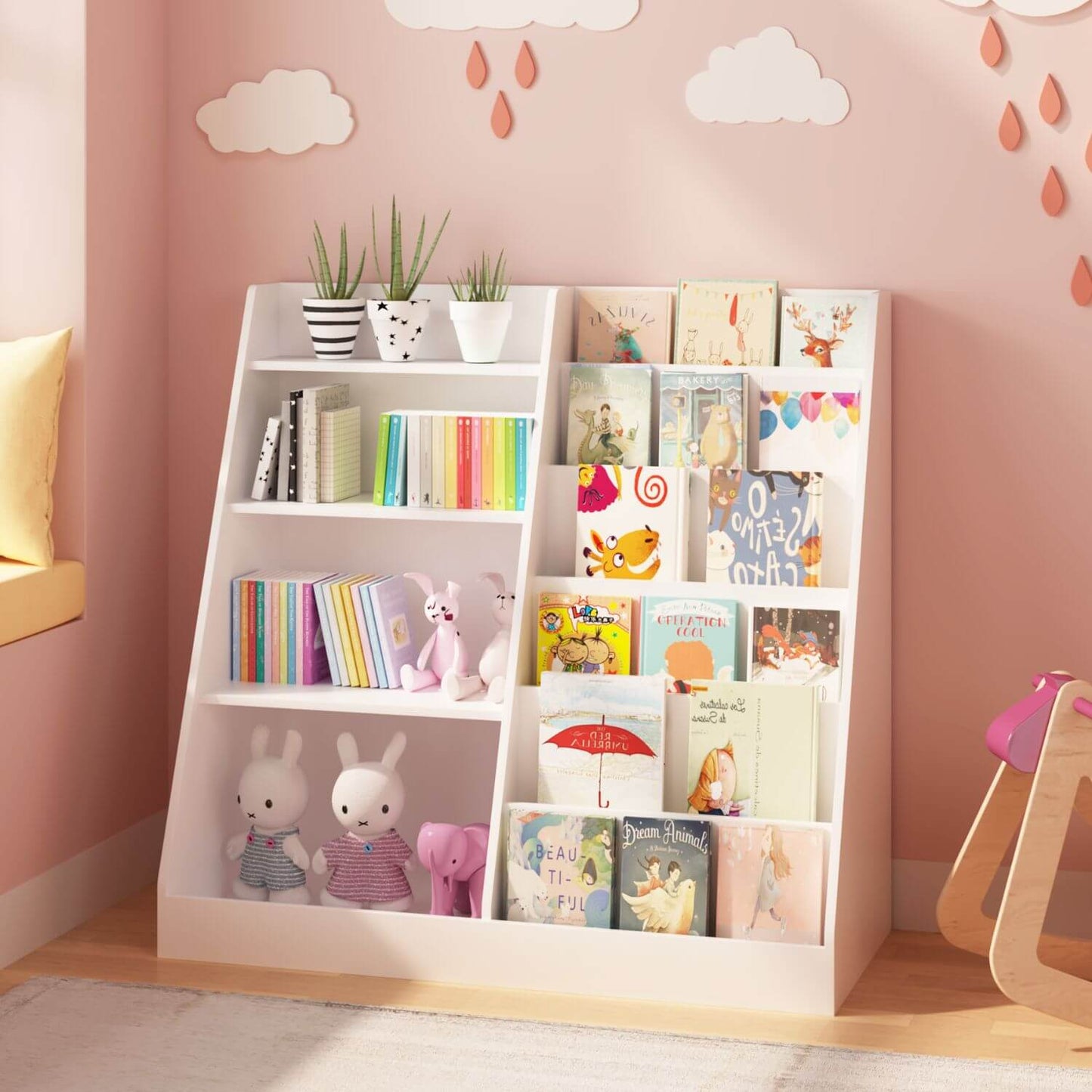 White children's bookshelf with books and toys against a pink wall with cloud decorations