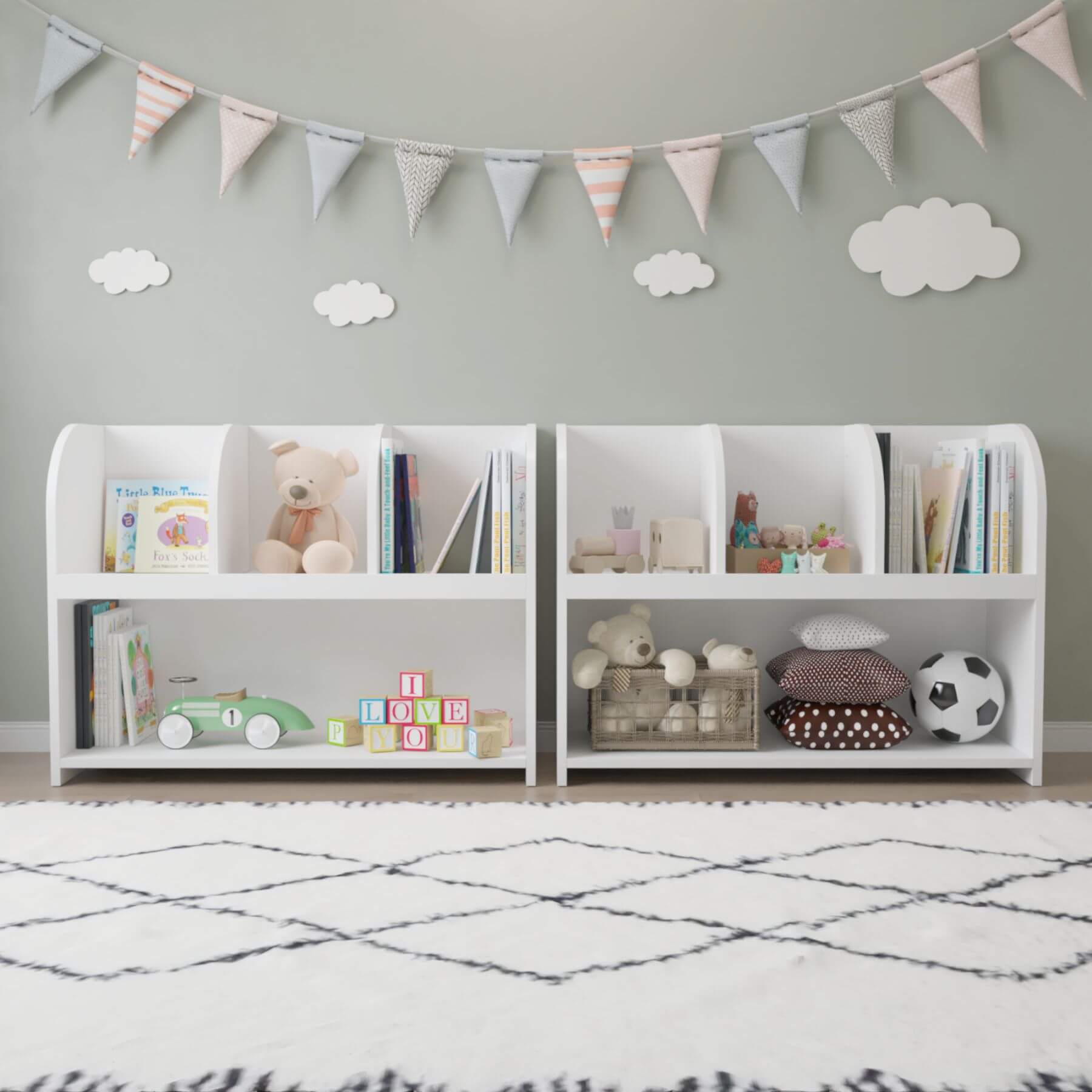 Children's room with white bookshelves filled with books, toys, and decorative items, featuring a banner and cloud decorations on the wall.
