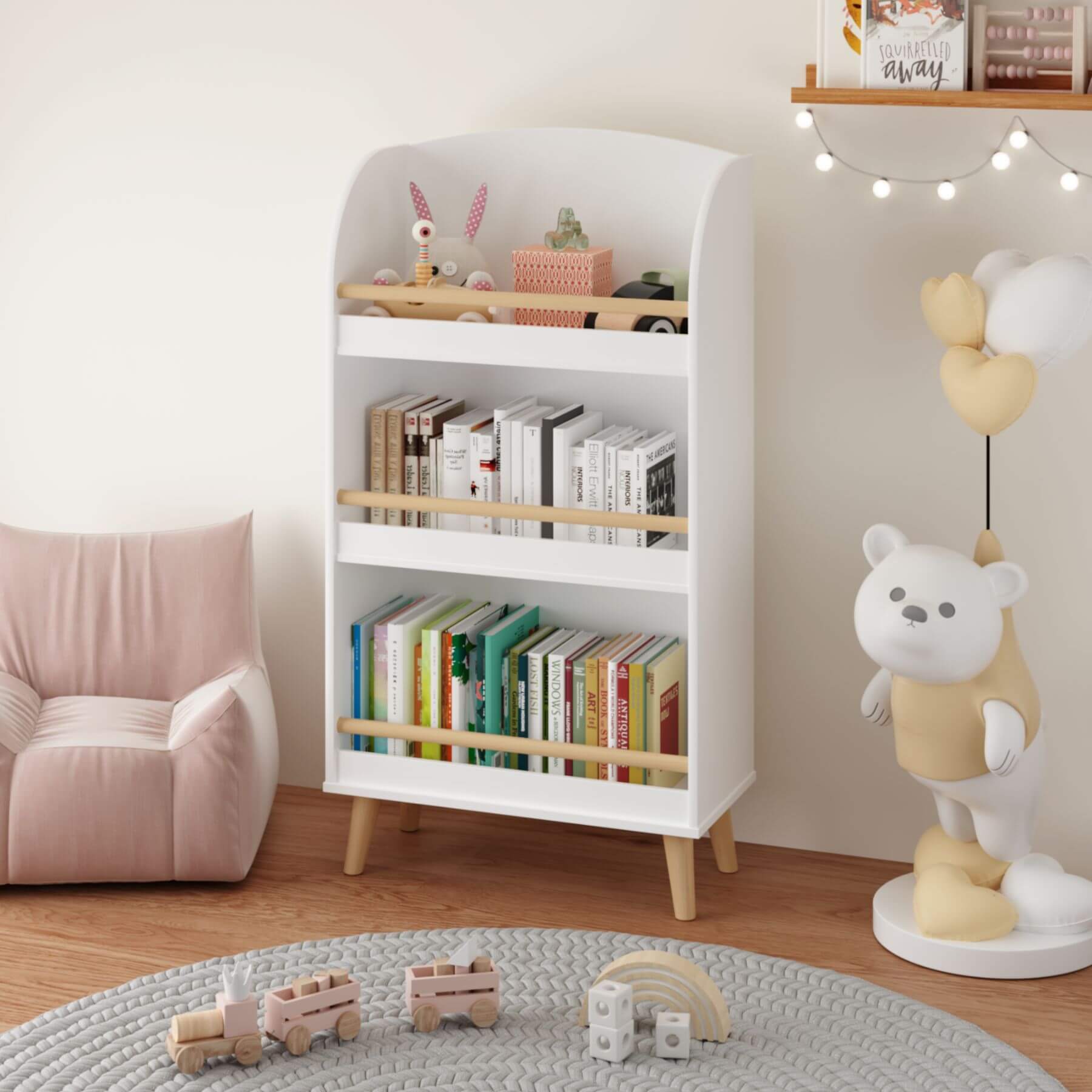 White bookshelf with books and toys in a room with a pink chair and teddy bear decoration.