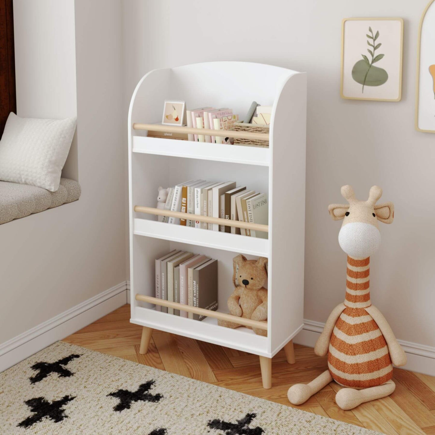 White bookshelf with wooden shelves in a room with a teddy bear and plush giraffe toy.