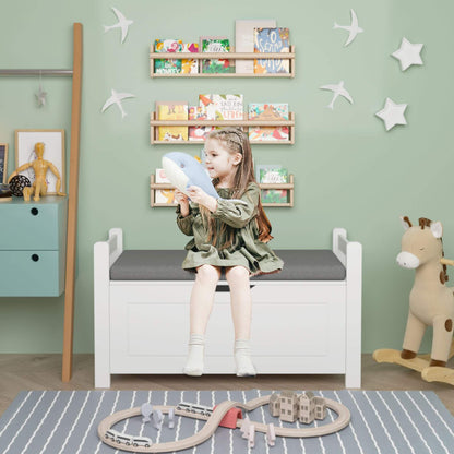 Child sitting on MOONRIVER Kids Toy Box Chest with a gray cushion, holding a blue toy, in a room with green walls, star decorations, and children's furniture.
