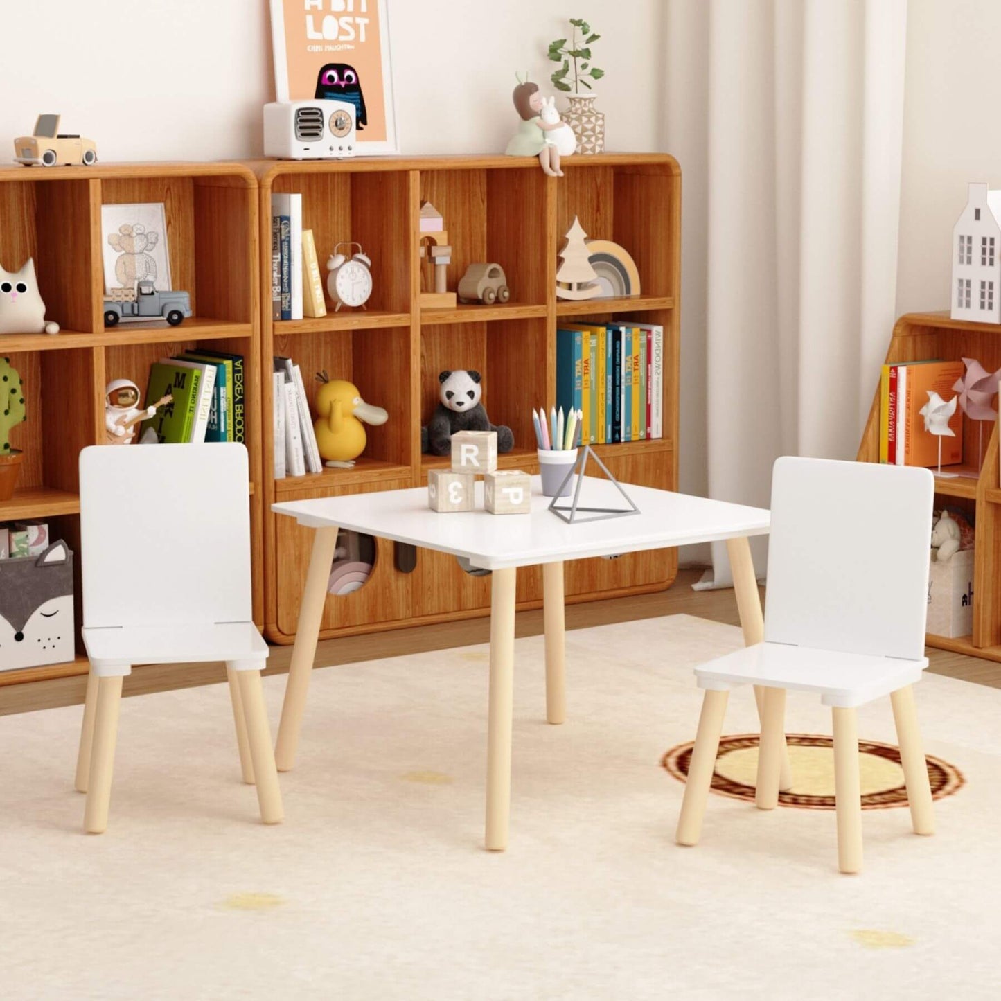 MOONRIVER Wooden Kids Table and 2 Chairs Set - White in a room with wooden bookshelf and decorative items.
