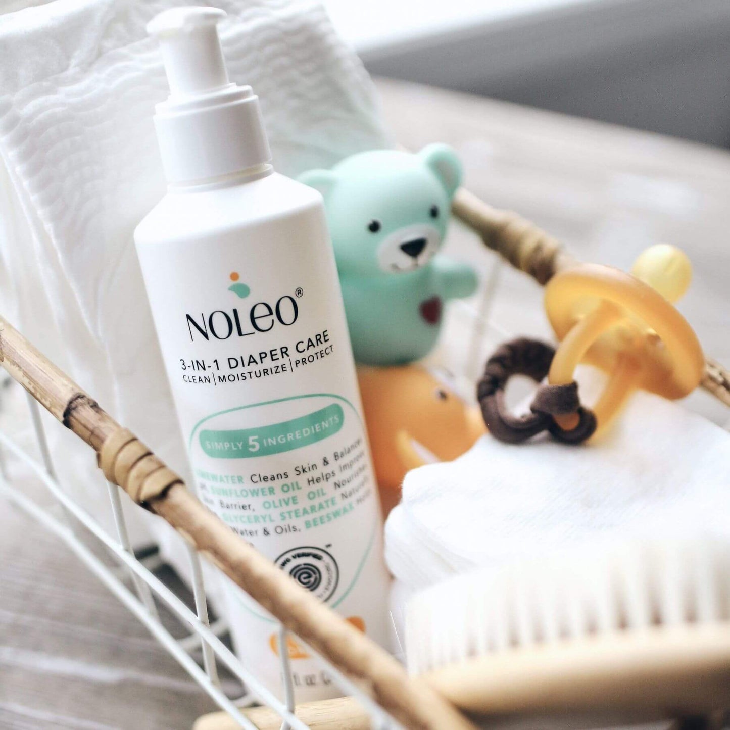 Noleo 3-in-1 Diaper Care bottle on a white surface with toys in the background